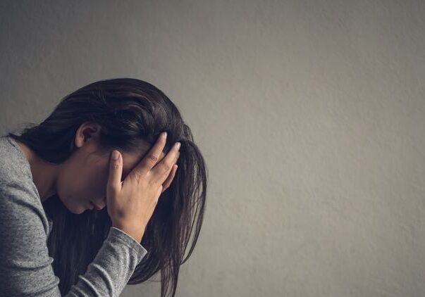 Woman holding head in hands, appearing upset